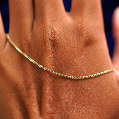 A solid gold Mini Miami Bracelet resting on the back of a model's hand