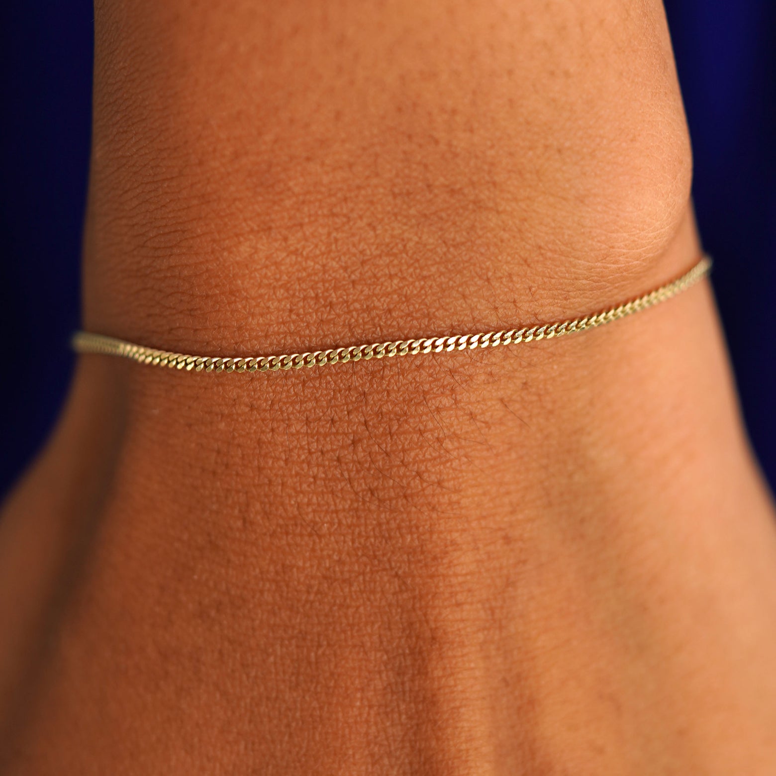 Close up view of a model's wrist wearing a solid yellow gold Mini Miami Bracelet