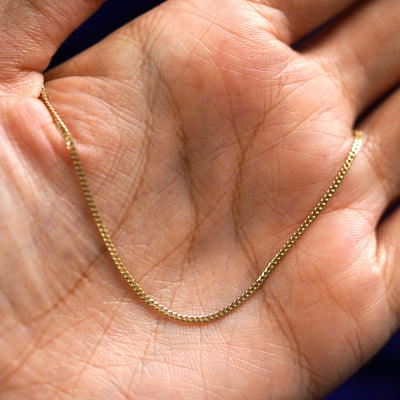 A yellow gold Mini Miami Bracelet draped on a model's palm