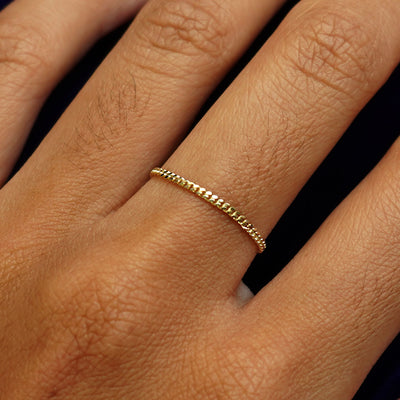 Close up view of a model's hand wearing a solid yellow gold Mini Miami Ring