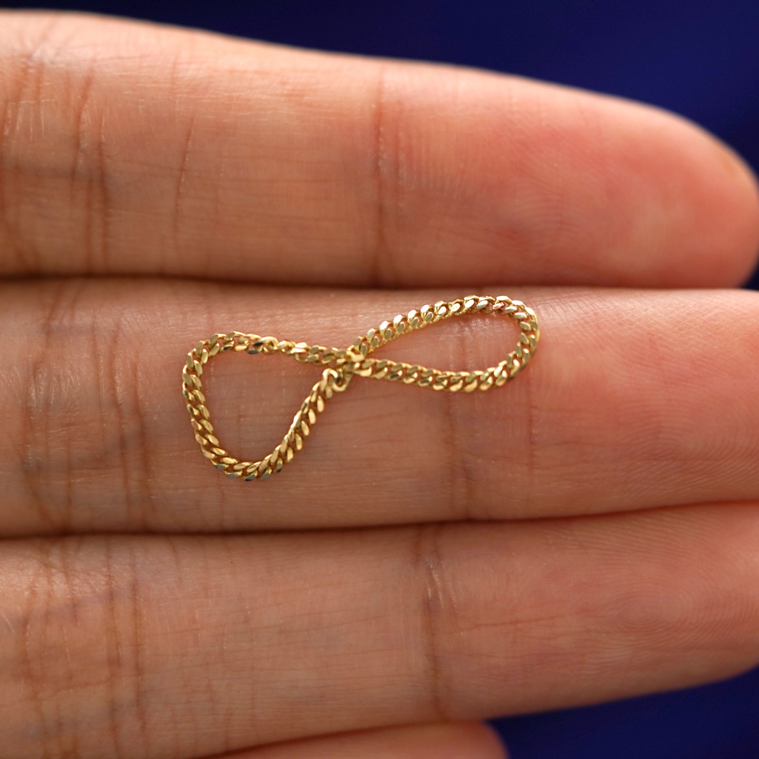 A solid yellow gold Mini Miami Ring twisted a model's finger