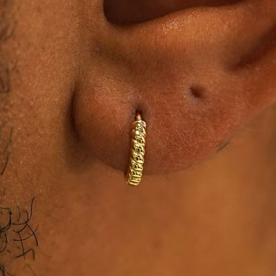 Close up view of a model's ear wearing a 14k gold Mini Rope Huggie Hoop Earring