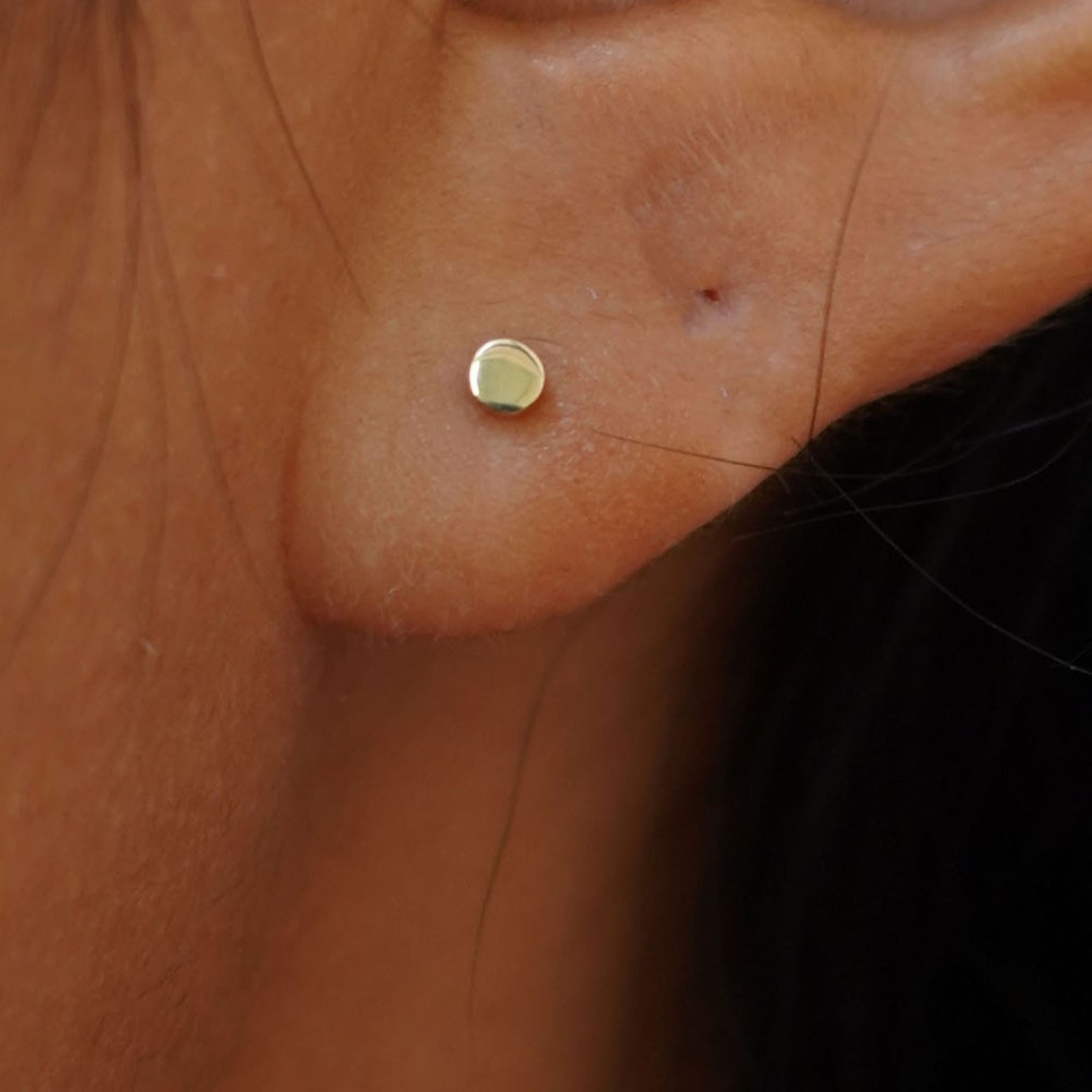 Close up view of a model's ear wearing a yellow gold Mini Circle Earring