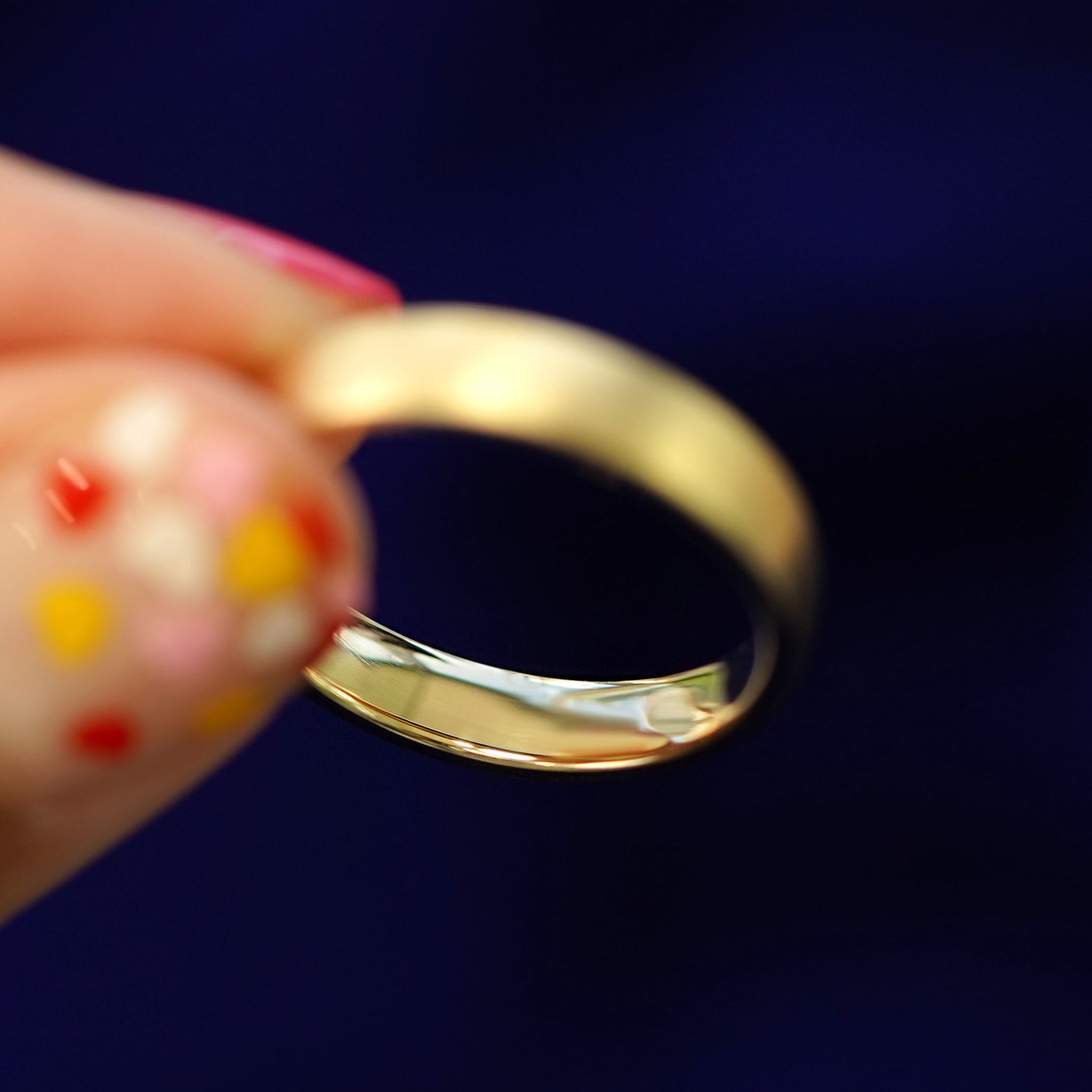 A model holding a 14k gold Mix Matte Band tilted to show the inside of the band