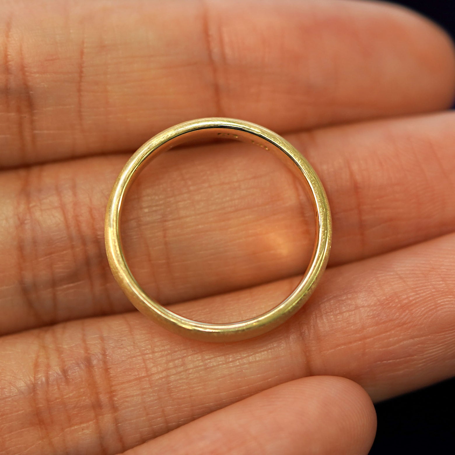 A yellow gold Mix Matte Band in a model's hand showing the thickness of the band