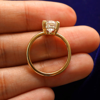 A Oval Moissanite Halo Ring in a model's hand showing the thickness of the band and the height of the ring