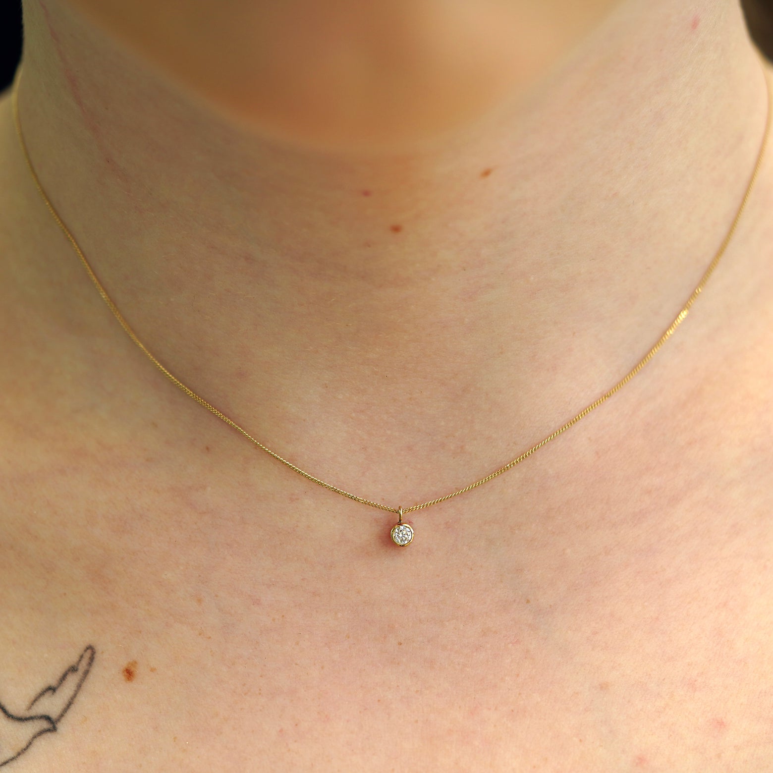 A model's neck wearing a solid 14k yellow gold Moissanite necklace