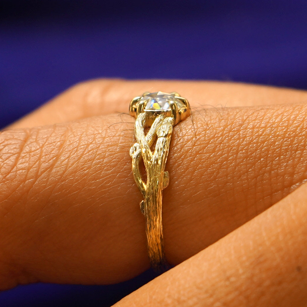 Side view of a Moissanite Branches Ring on a model's finger showing three braided tree branches going to the center stone
