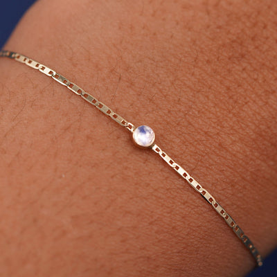 Close up view of a models wrist wearing 14k yellow gold Moonstone Bracelet