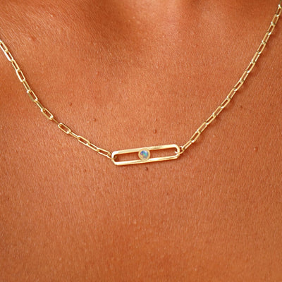 Close up view of a model wearing a yellow gold Dancing Gemstone necklace with a single Opal