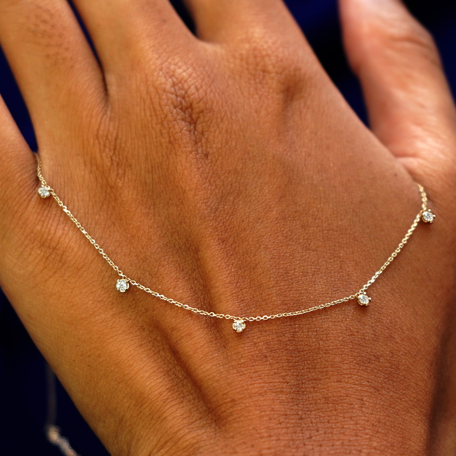 A solid gold 5 Diamond Cable Necklace resting on the back of a model's hand