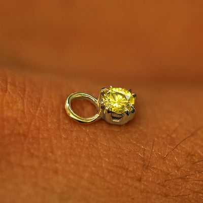 A solid yellow gold Yellow Diamond Charm for earring resting on the back of a model's hand