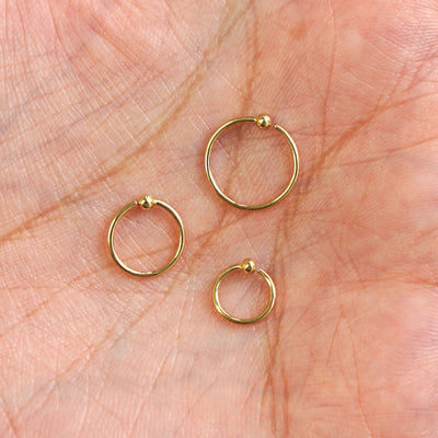 Three versions of the Nose Ring Hoop showing the 6mm, 8mm and 10mm sizes in the palm of a model's hand