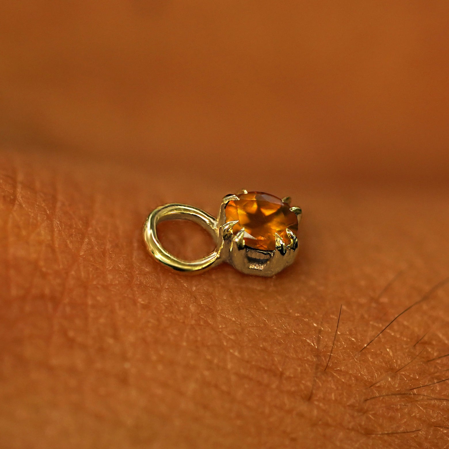 A solid yellow gold Citrine Charm for earring resting on the back of a model's hand