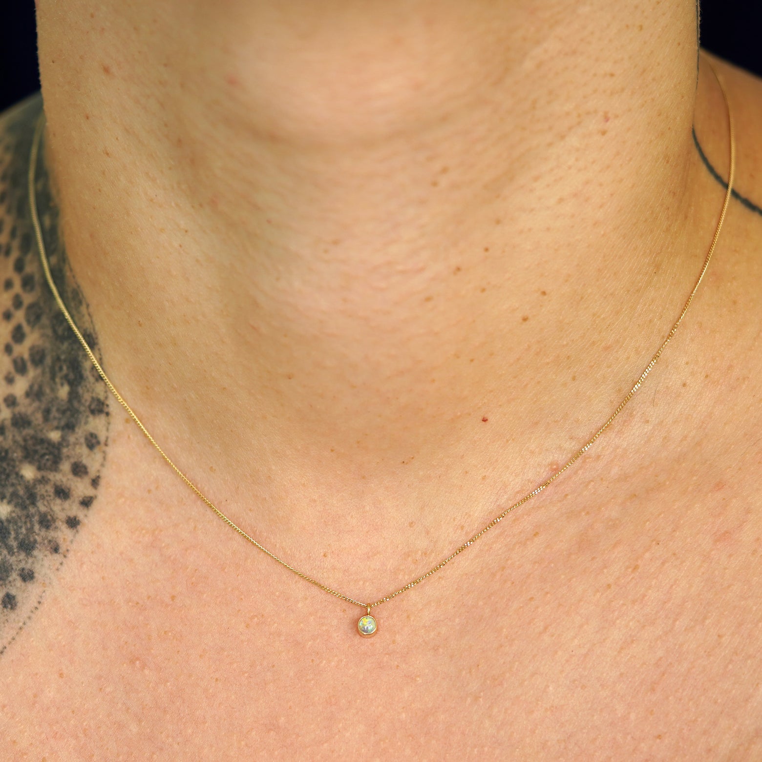 A model's neck wearing a solid 14k yellow gold Opal necklace