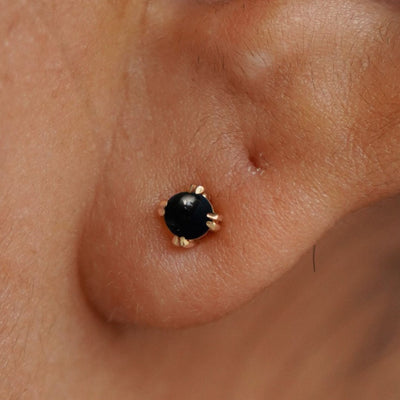 Close up view of a model's ear wearing a 14k yellow gold Onyx Earring