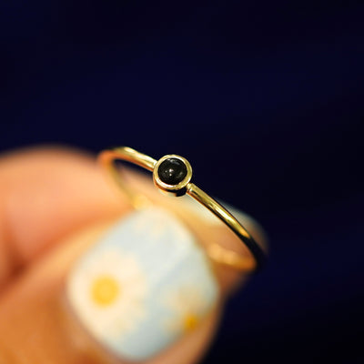 A model holding an Onyx Ring tilted to show the bezel setting