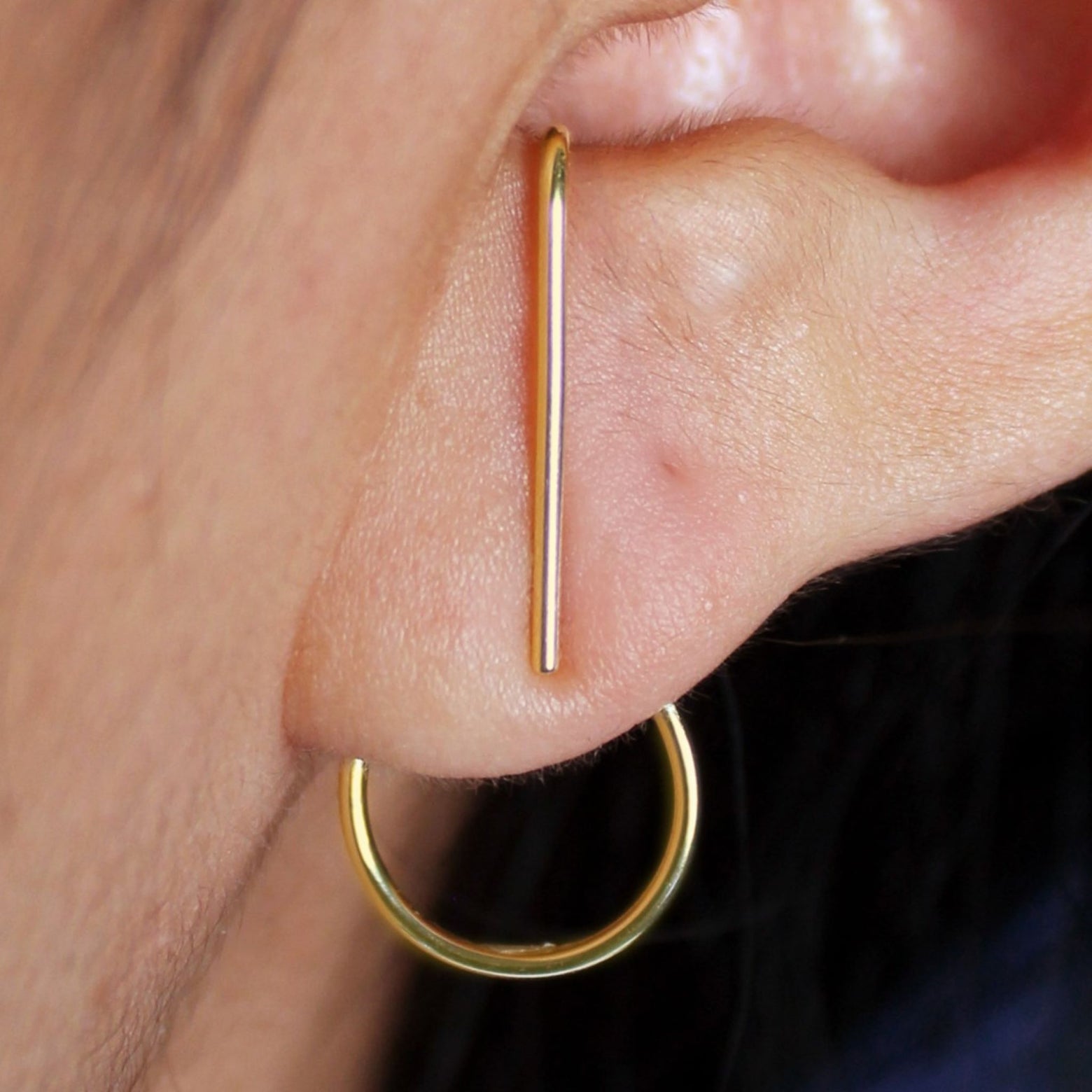 Close up view of a model's ear wearing a solid 14k yellow gold Open Circle Jacket with a Suspender Earring