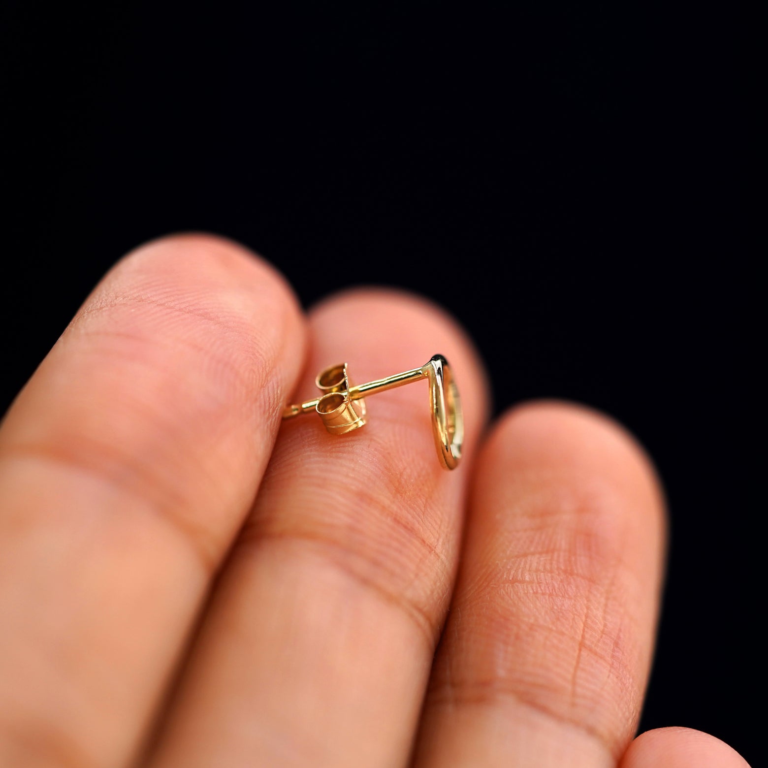 A 14k gold Open Circle Earring sitting sideways on a model's fingertips to show detail
