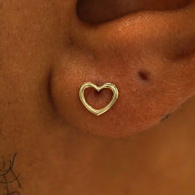Close up view of a model's ear wearing a 14k gold Heart Earring