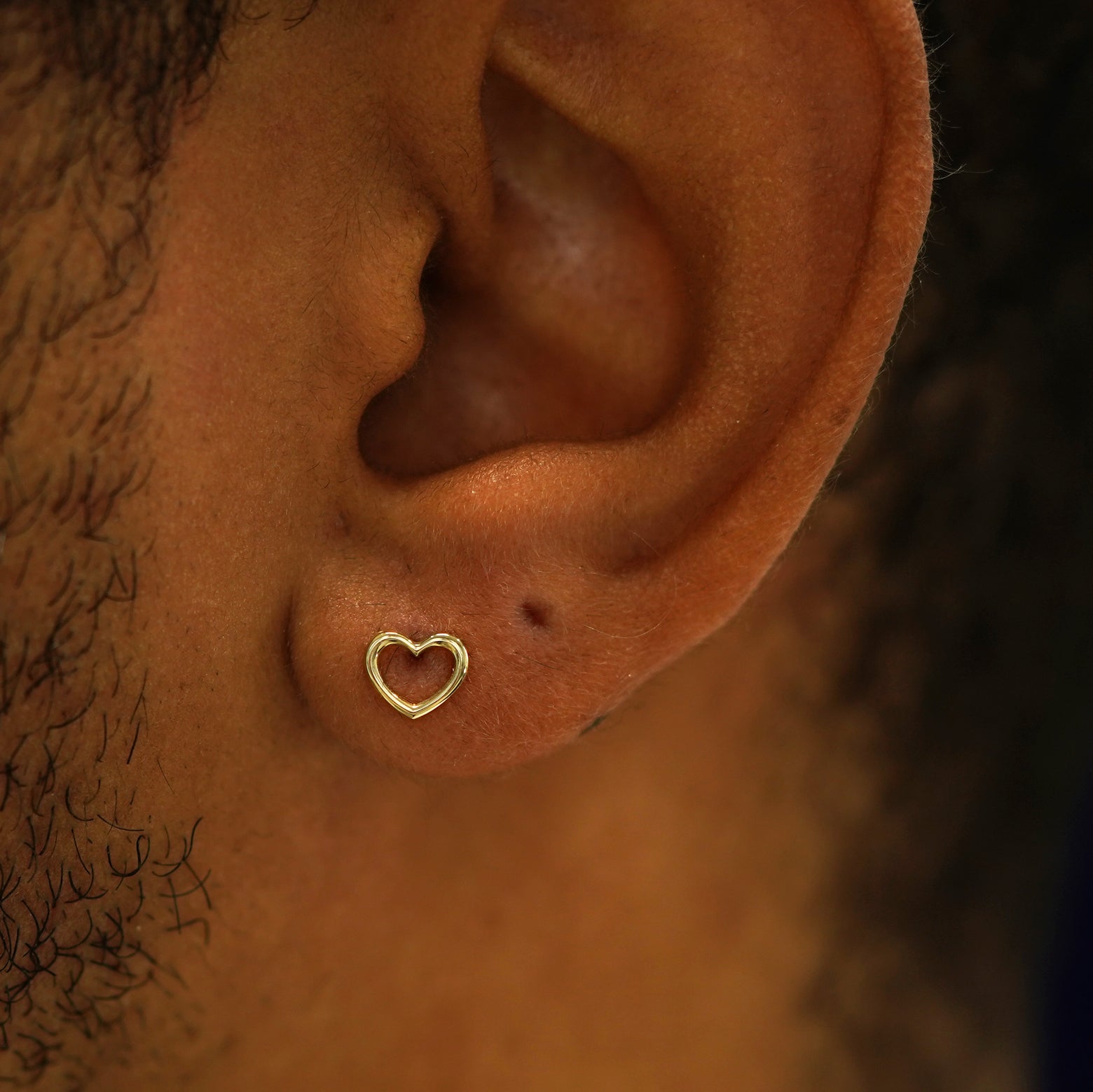 A model's ear wearing a 14k gold open Heart Earring