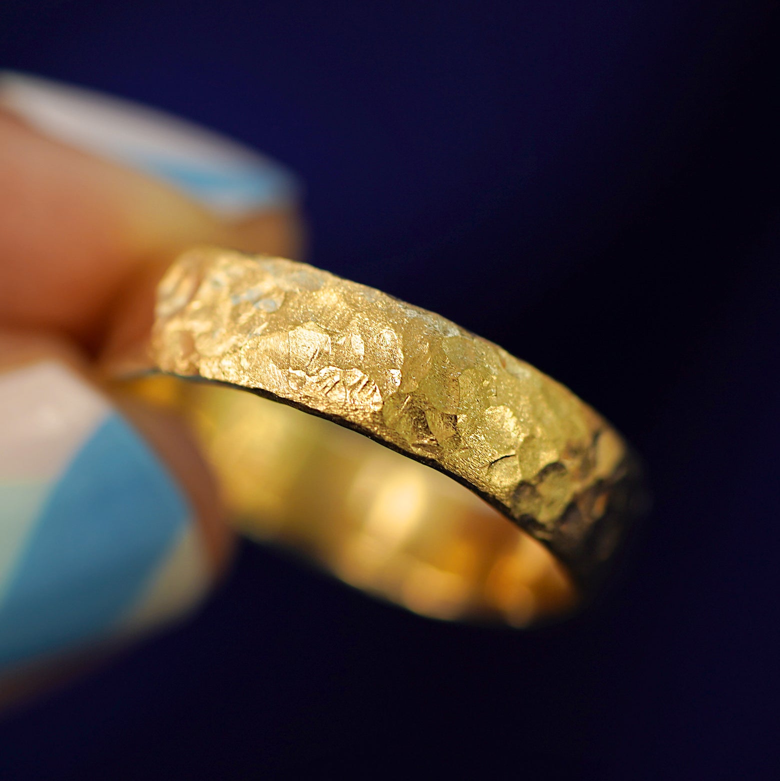 A model holding a 14k gold Organic Band tilted to show the side of the ring