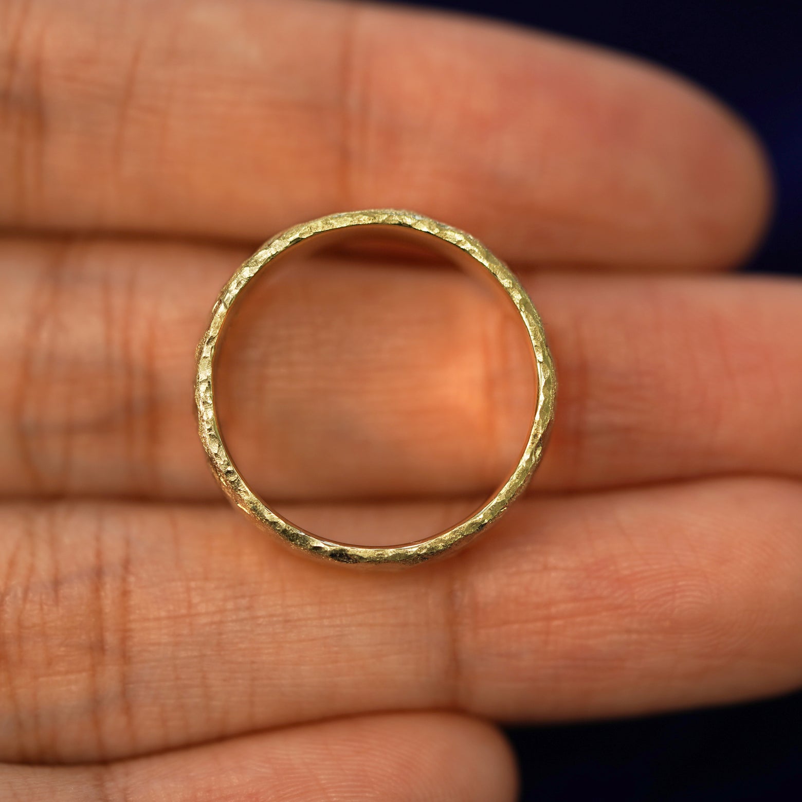 A yellow gold Organic Band in a model's hand showing the thickness of the band