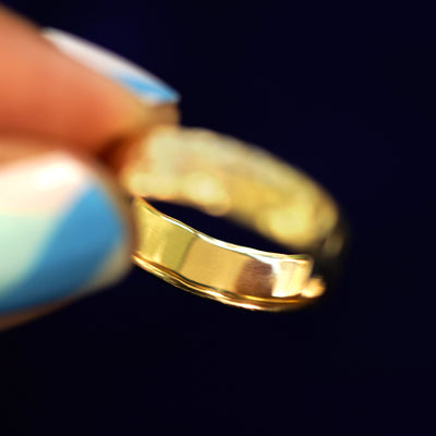 A model holding a 14k gold Organic Band tilted to show the inside of the band