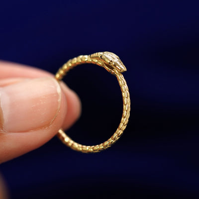 A model holding a Ouroboros Snake RIng tilted to show the side of the ring