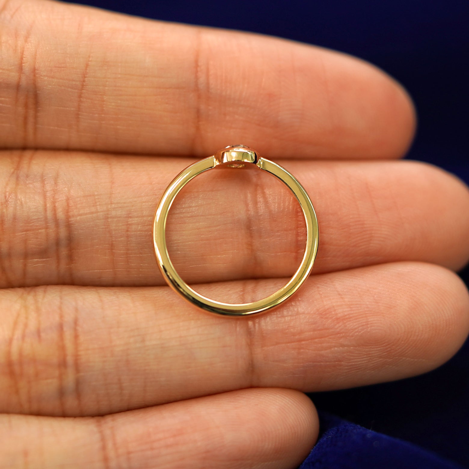 A yellow gold Oval Champagne Diamond Ring in a model's hand showing the thickness of the band