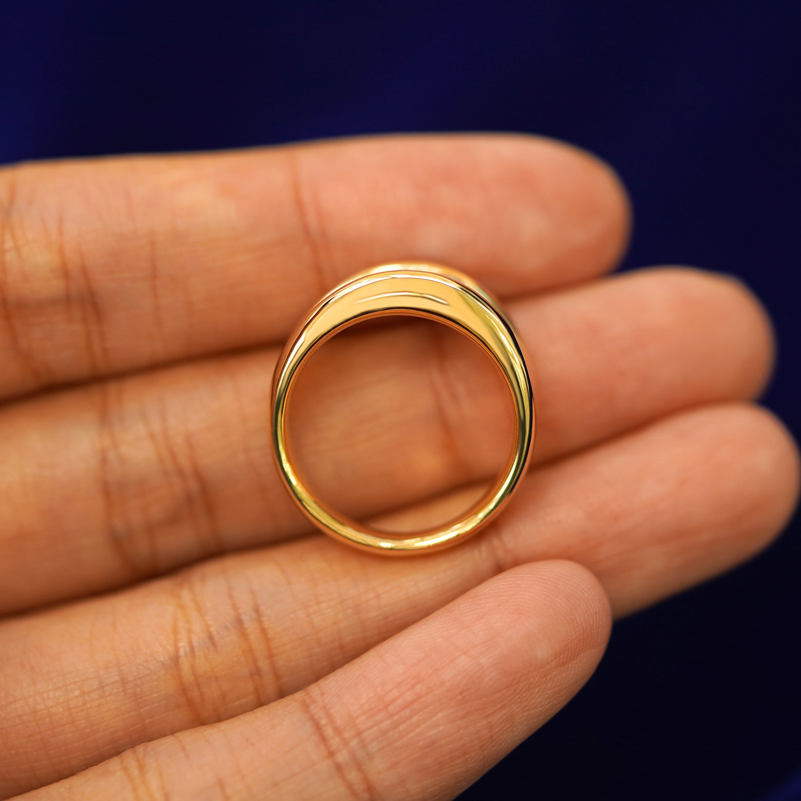 A yellow gold Oval Lab Diamond Tension Ring in a model's hand showing the thickness of the band