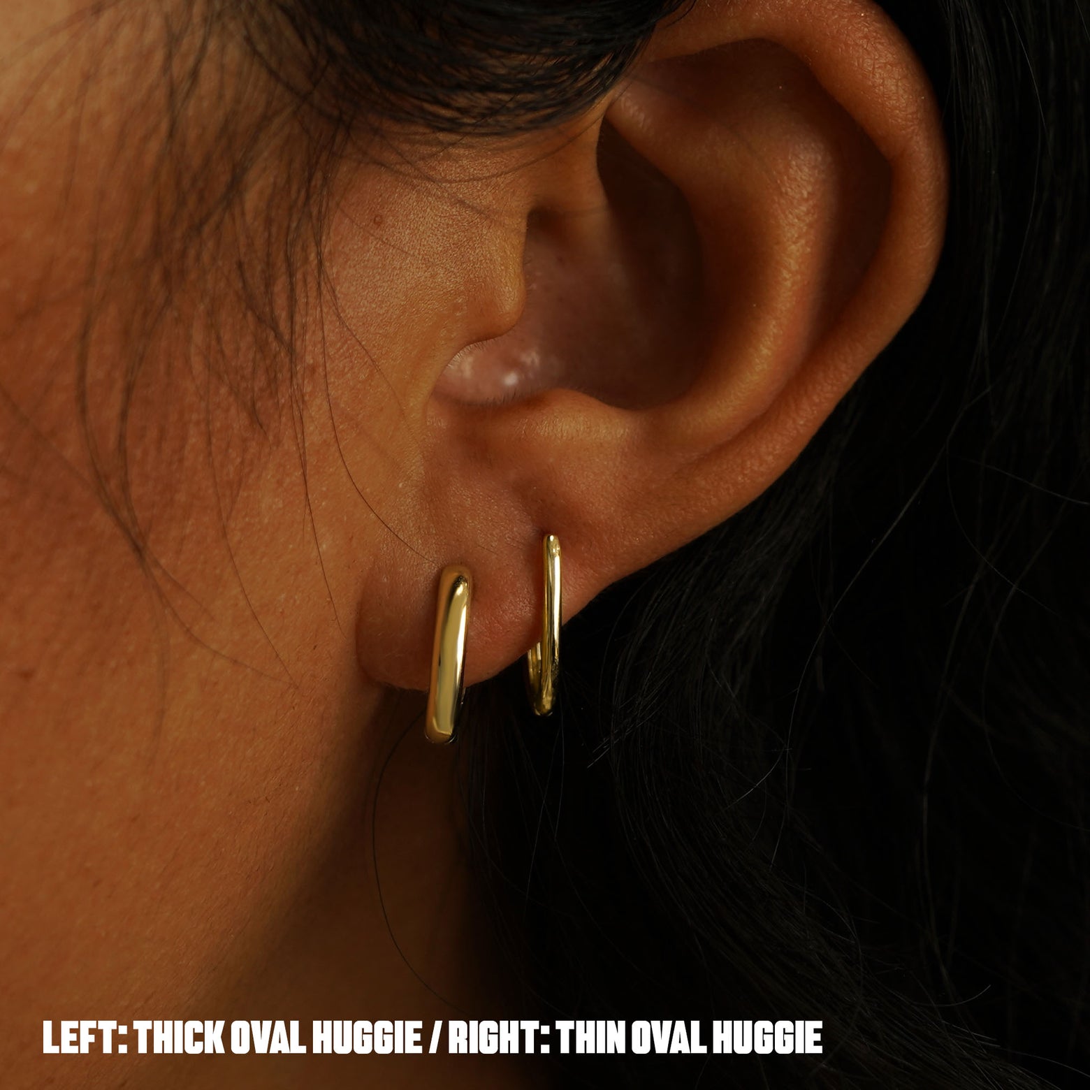 A model's ear wearing a  yellow gold Thick Oval Huggie Hoop and a Thin Oval Huggie Hoop in two piercings