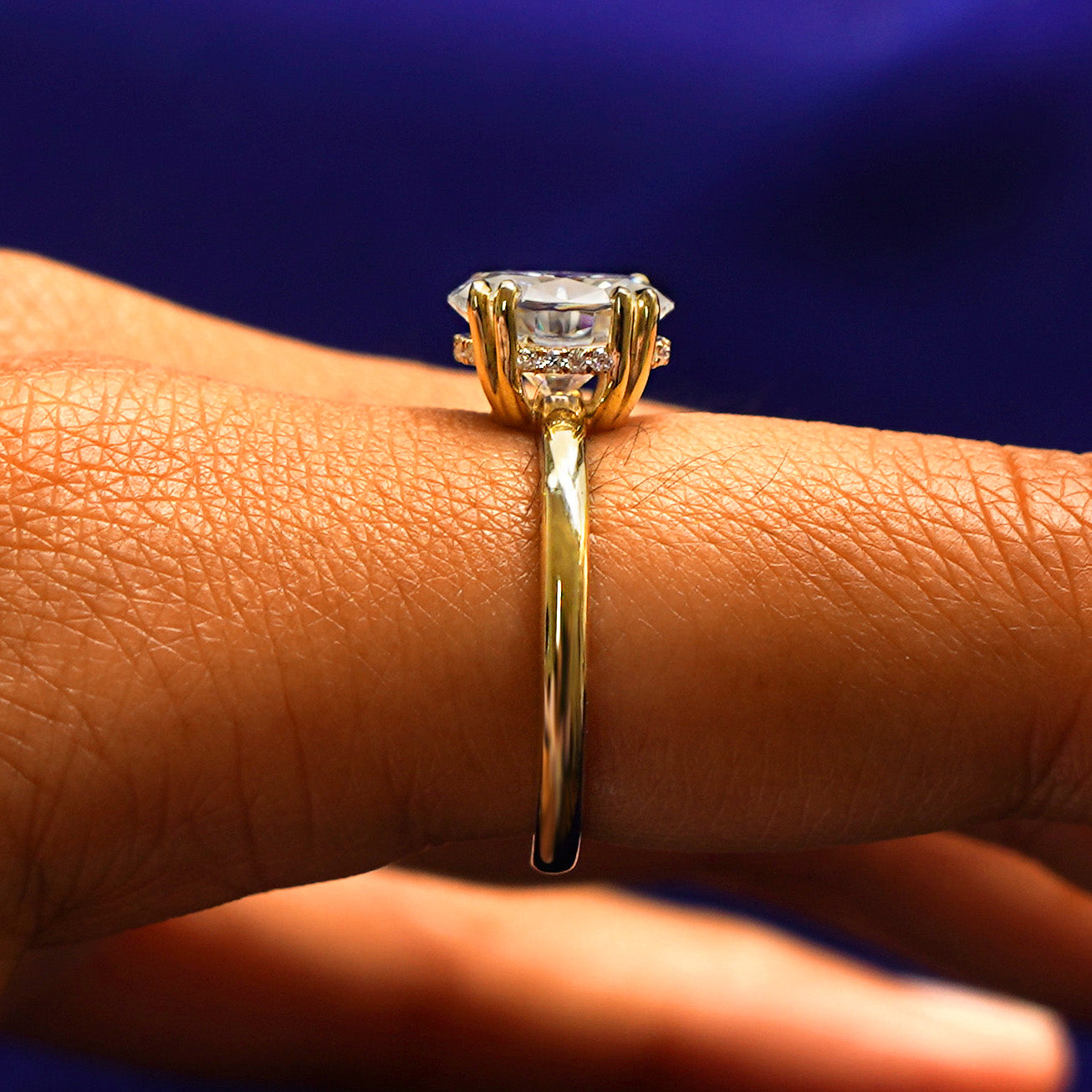 Side view of a Oval Moissanite Halo Ring on a model's finger to show the hidden halo