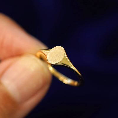 A model holding a Oval Signet Ring tilted to show the detail of the top of the ring