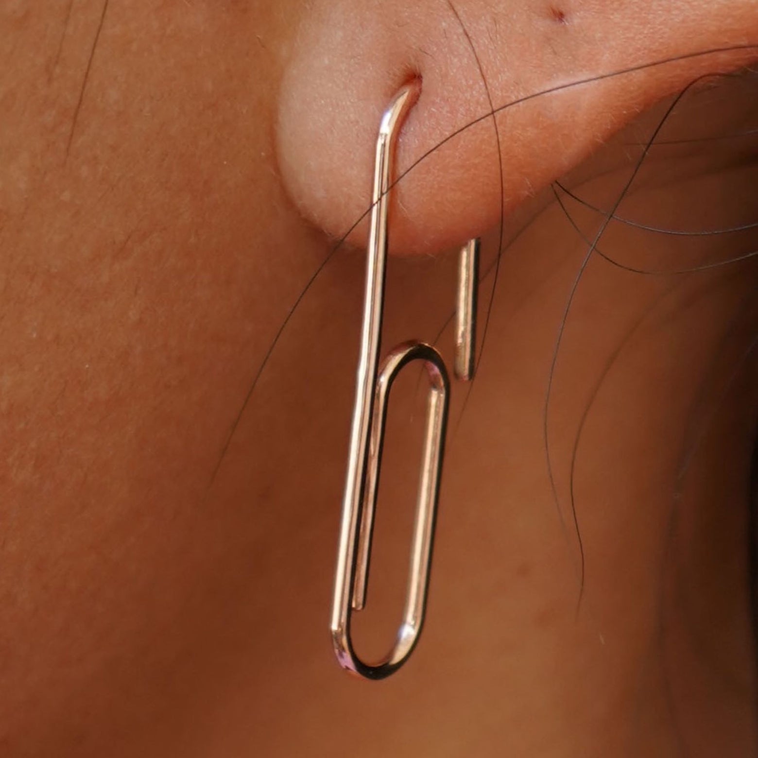 Close up view of a model's ear wearing a yellow gold Not A Paper Clip Earring