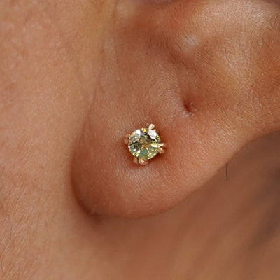 Close up view of a model's ear wearing a 14k yellow gold Peridot Earring