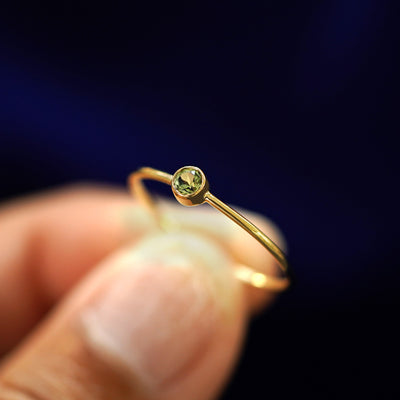 A model holding a Peridot Ring tilted to show the bezel setting