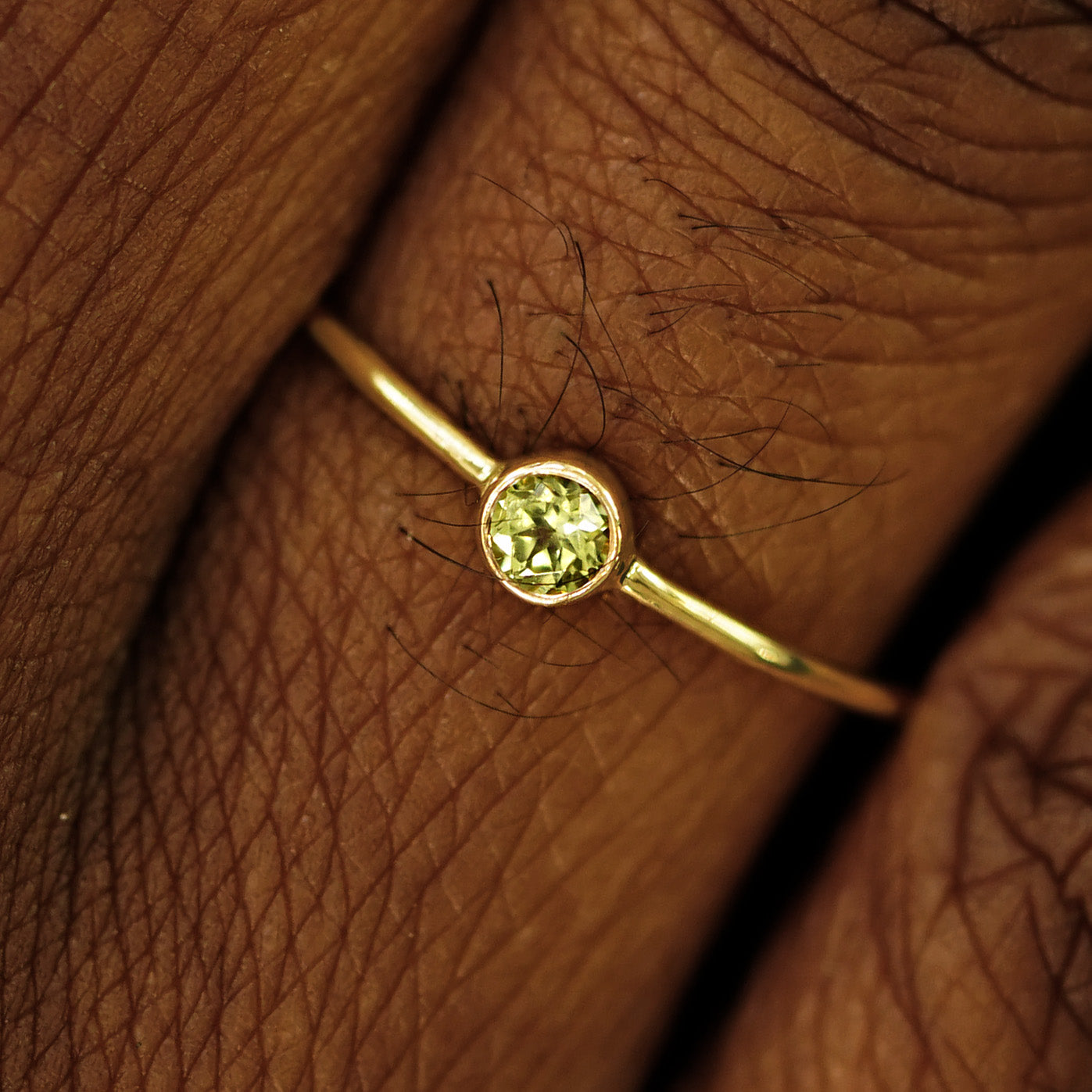 Close up view of a model's fingers wearing a 14k yellow gold Peridot Ring