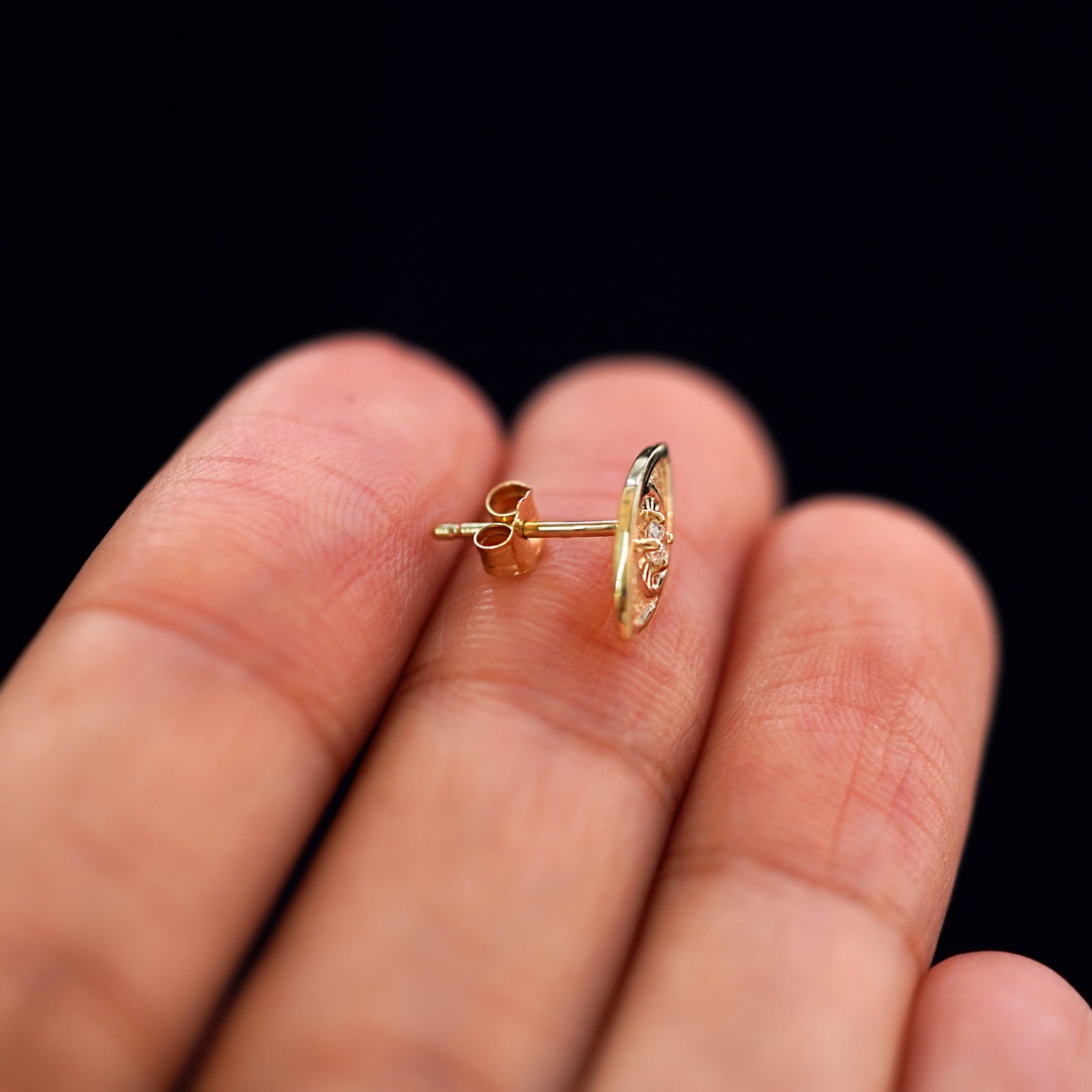 A 14k gold Dog Earring sitting sideways on a model's fingertips to show detail