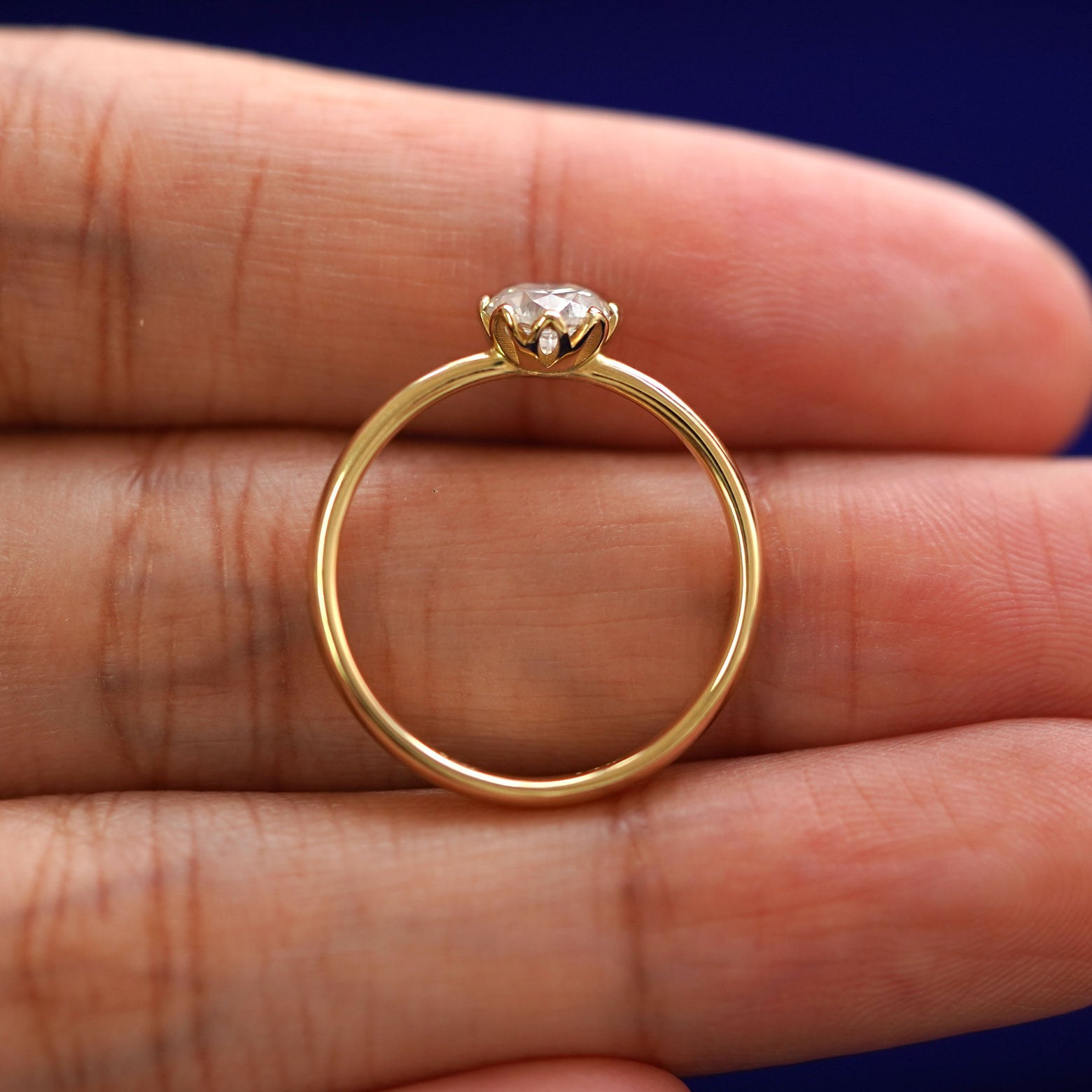 A yellow gold Diamond Petal Ring in a model's hand showing the thickness of the band