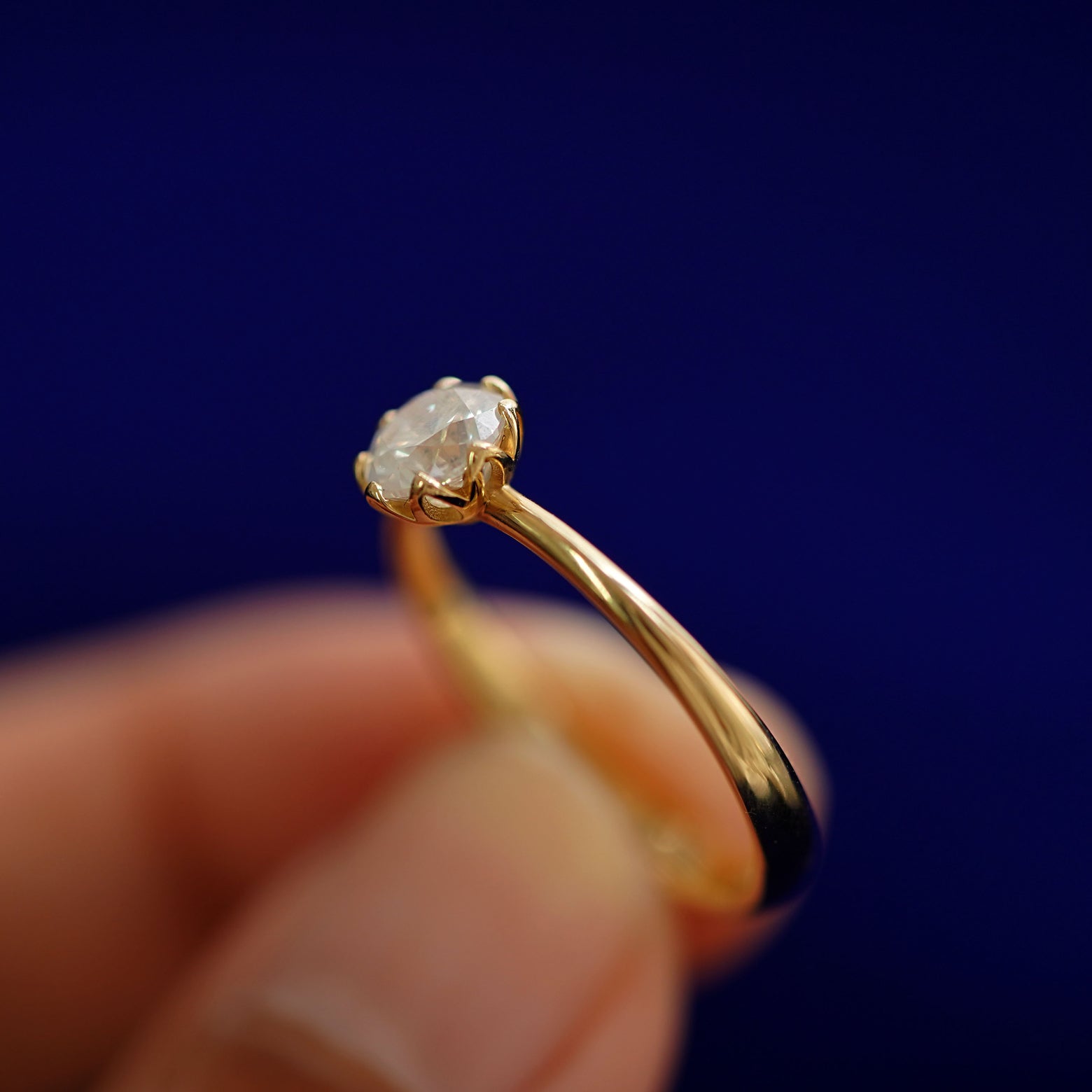 A model holding a Diamond Petal Ring tilted to show the side of the ring