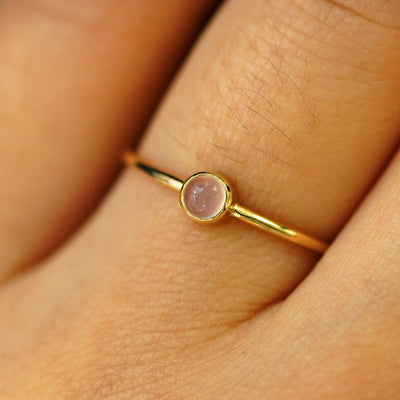 Close up view of a model's hand wearing a yellow gold Rose Quartz Ring