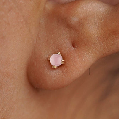 Close up view of a model's ear wearing a 14k yellow gold Rose Quartz Earring