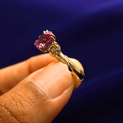 A model holding a Pink Sapphire Roses Ring tilted to show the vine detailing on the side of the ring
