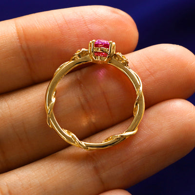 A yellow gold Pink Sapphire Roses Ring in a model's hand showing the thickness of the band