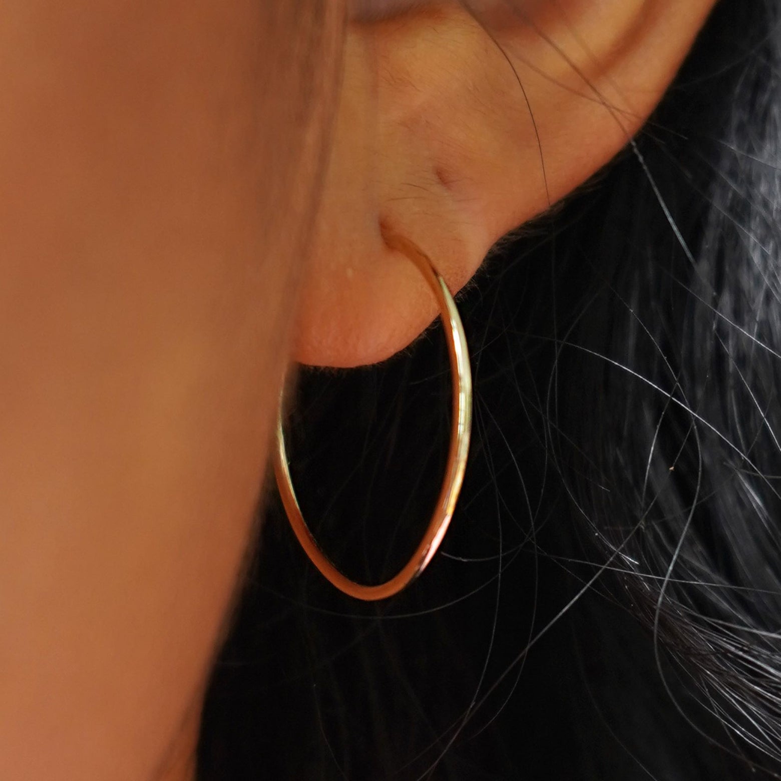 Close up view of a model's ear wearing a yellow gold Medium Hoop