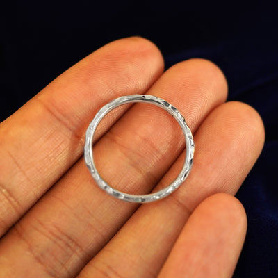 A Platinum Curvy Hammered Band resting on a model's fingers to show the thickness of the band