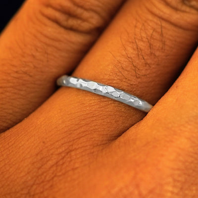 Close up view of a model's fingers wearing a 2mm 950 platinum Curvy Hammered Band