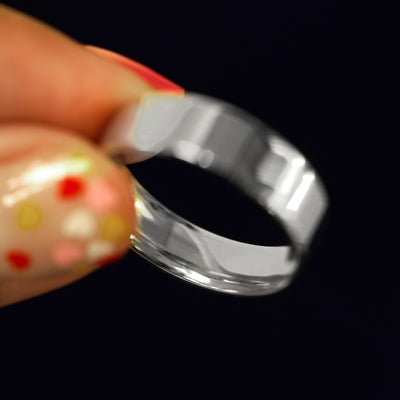 A model holding a Platinum Industrial Mirror Band tilted to show the inside of the band