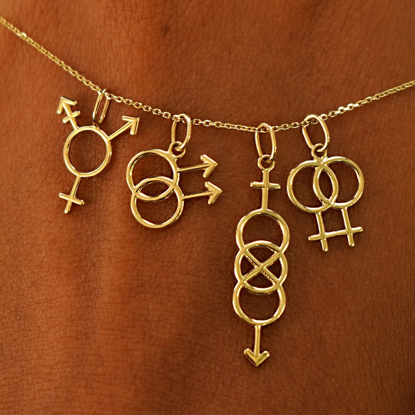 A model's wrist wearing yellow gold Transgender, Gay, Bisexual, and Lesbian Symbol Charms on a Cable Bracelet